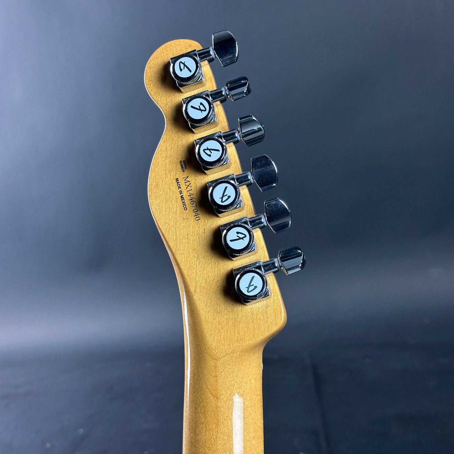 Guitar headstock with tuning pegs on a dark background