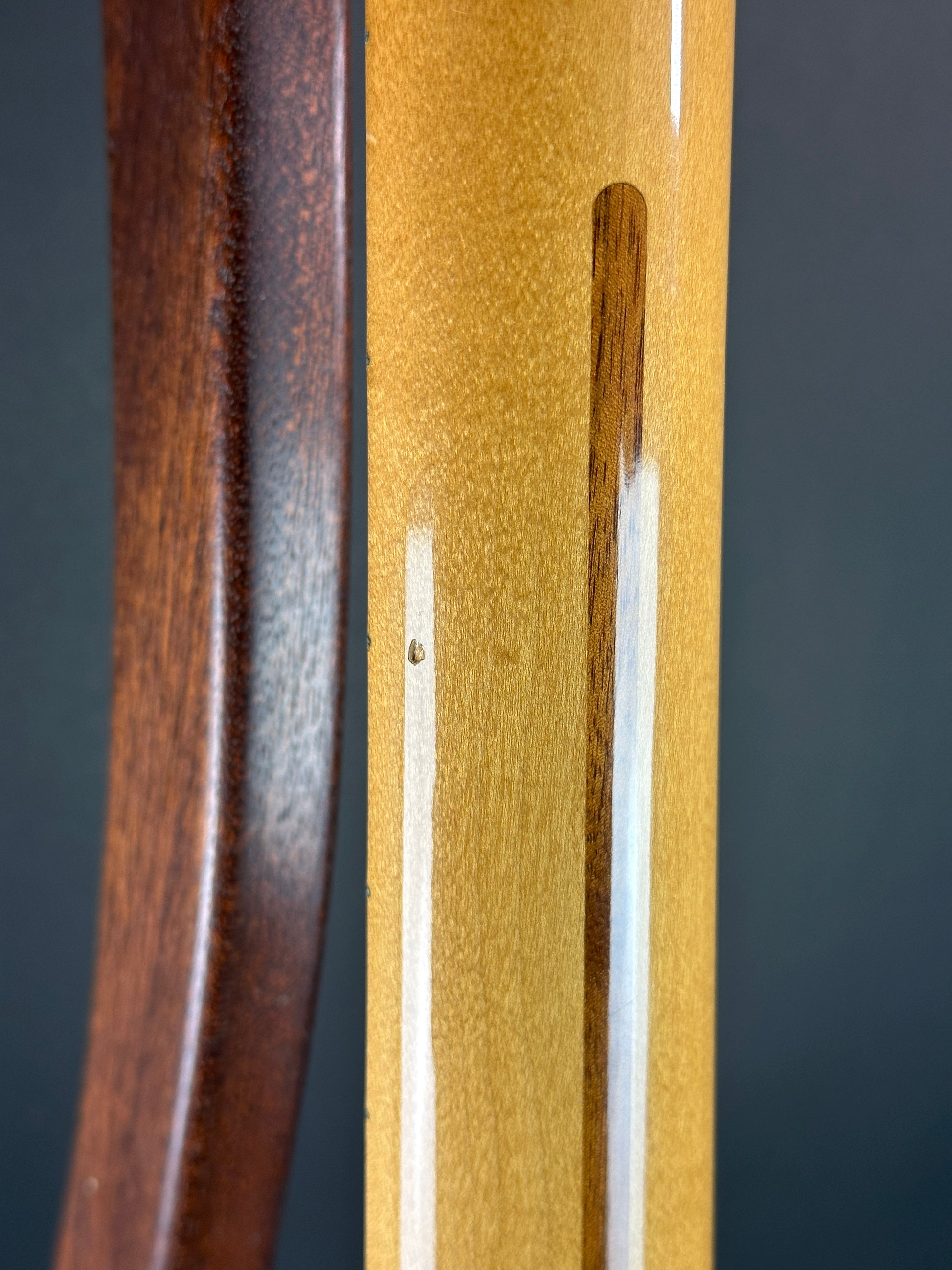 Close-up of a wooden object with a dark brown handle and light brown surface.