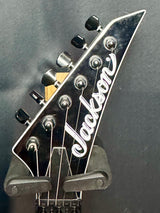 Close-up of a Jackson guitar headstock on a dark background