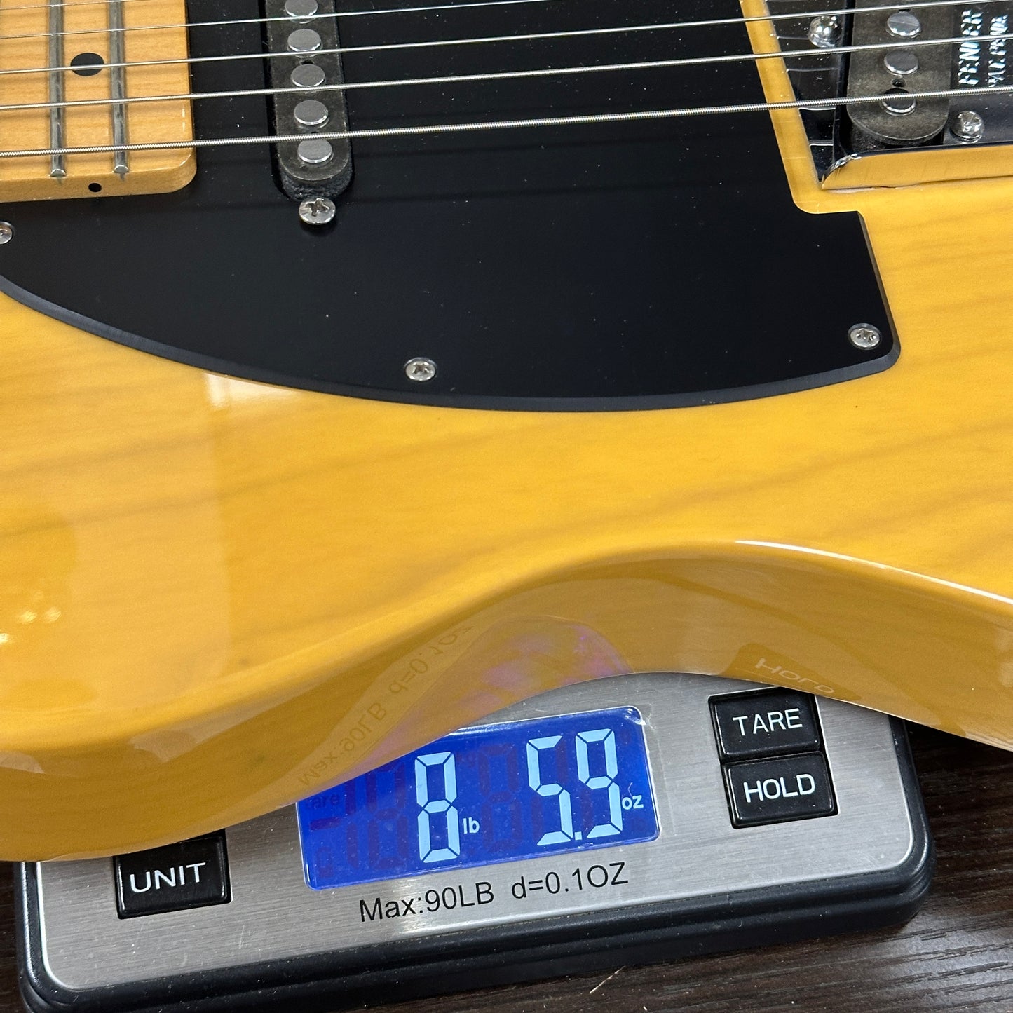 Yellow electric guitar on a digital scale displaying weight