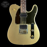 A gold-finish electric guitar with a black pickguard and chrome hardware, shown against a solid black background. A Tone Shop watermark is visible in the top-left corner.