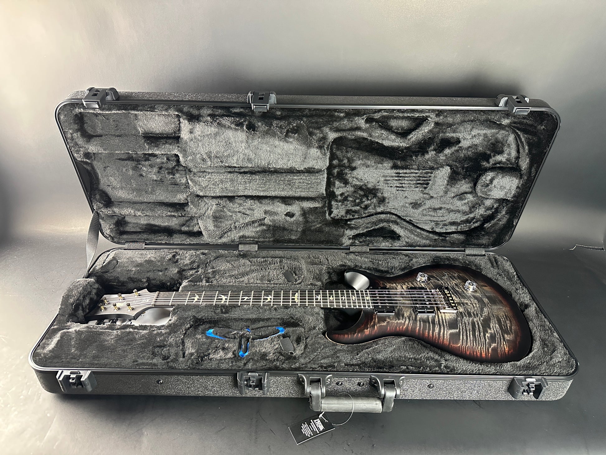 Guitar in an open hard-shell case on a gray background