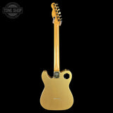 A gold-finish electric guitar shown from the back against a solid black background, with a Tone Shop watermark in the upper left corner.