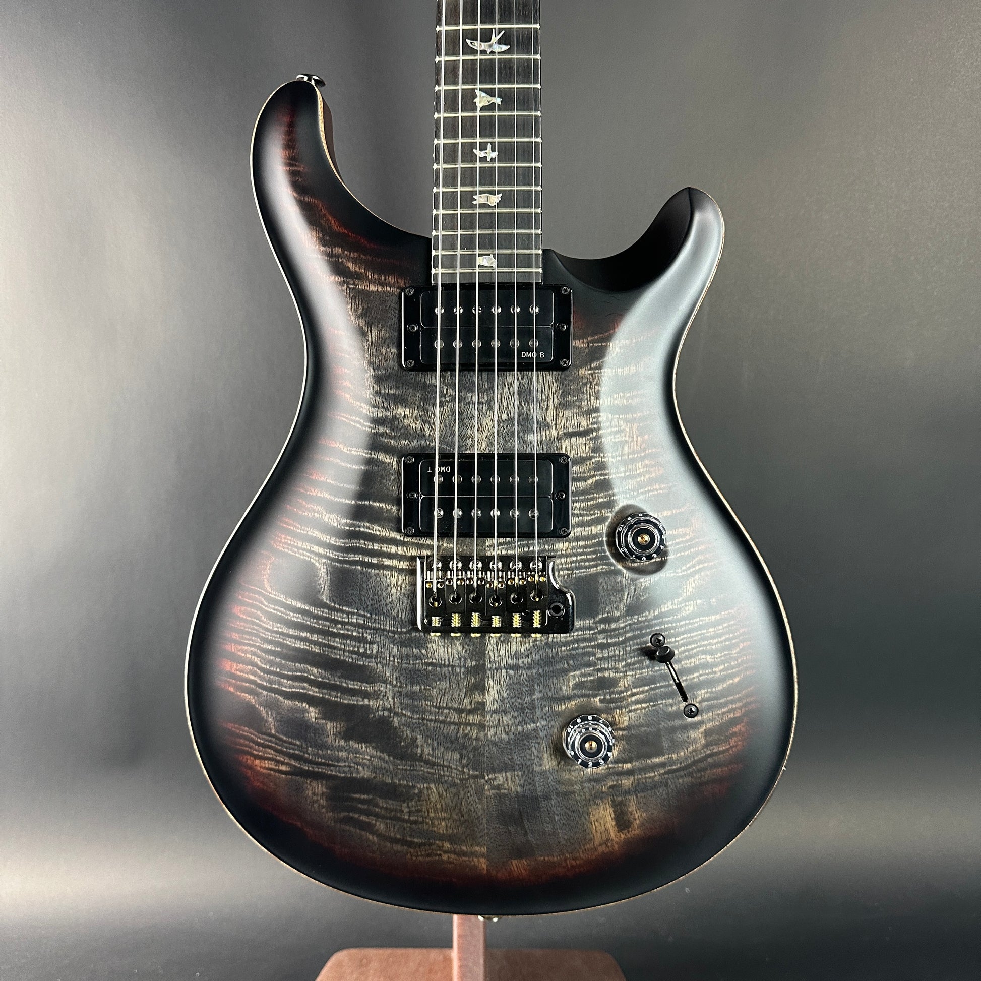 Electric guitar with a wood finish on a stand against a gray background