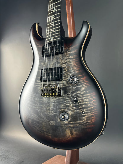 Close-up of a electric guitar with a dark, textured finish on a gray background