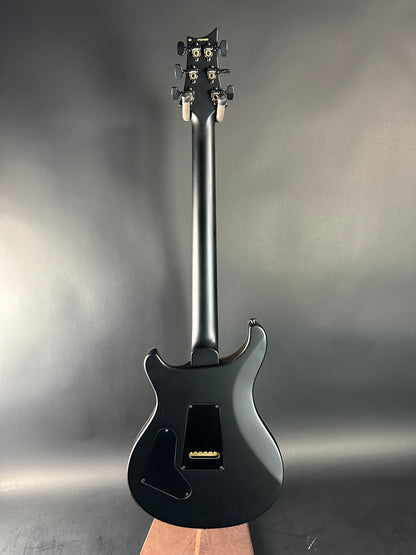 Black electric guitar on a reflective surface with a neutral background