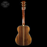 Back view of a wooden acoustic guitar with 'Tone Shop' logo in the corner.