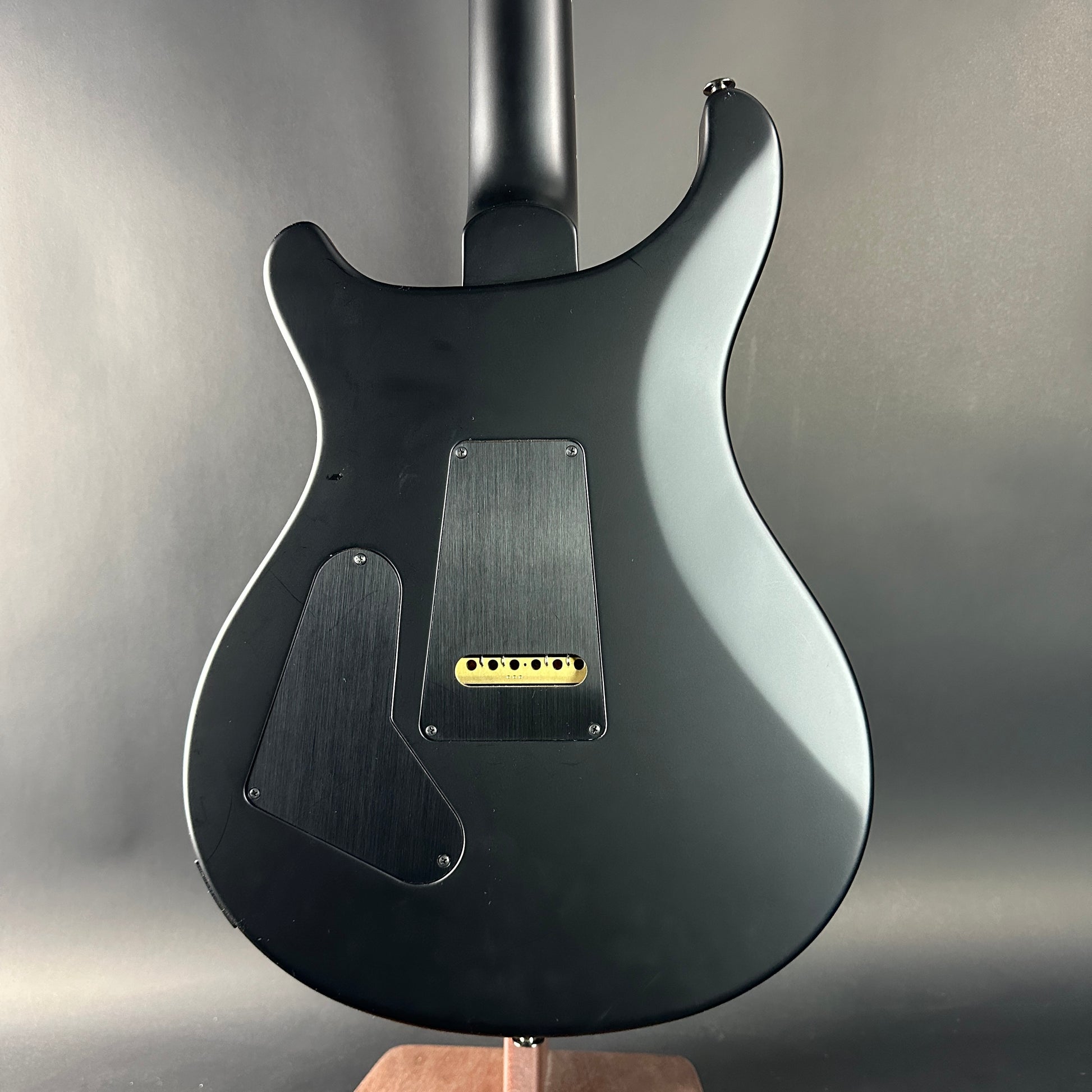 Black electric guitar on a stand against a gray background