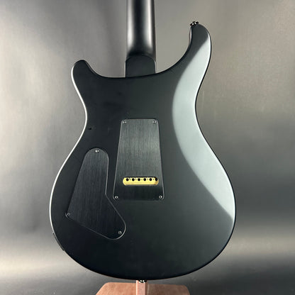 Black electric guitar on a stand against a gray background