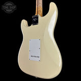 Glossy white electric guitar body with a visible brand label on a black background