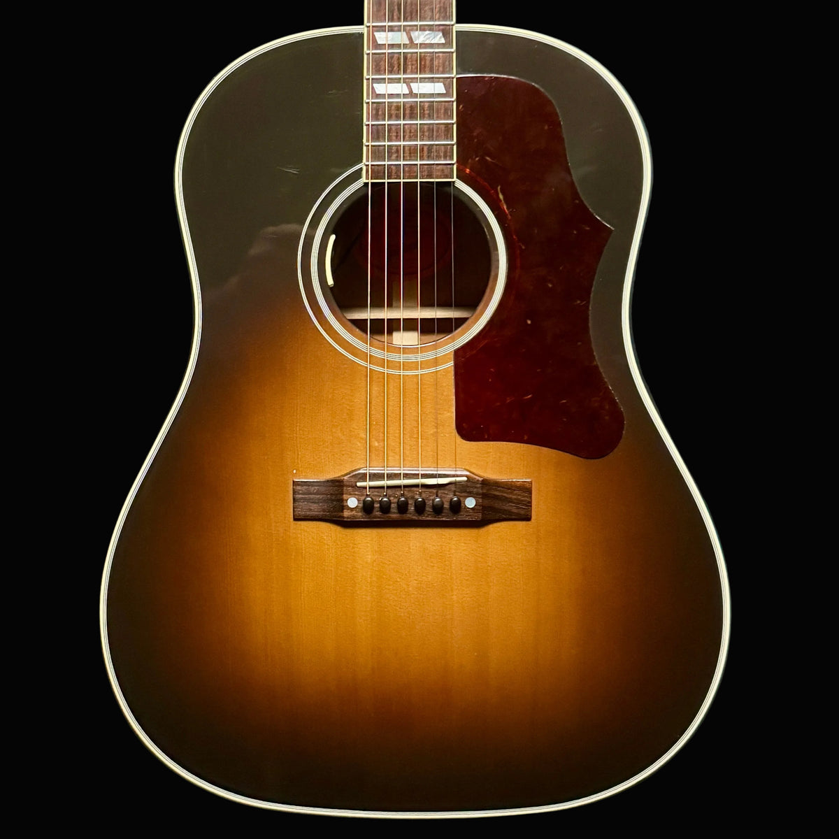 Acoustic guitar with a sunburst finish on a dark background