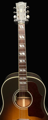 Acoustic guitar with a visible brand logo on a dark background