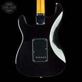 The back of a black electric guitar with a maple neck, featuring a glossy black finish, a white accent stripe, and a black pickguard, shown against a black background.