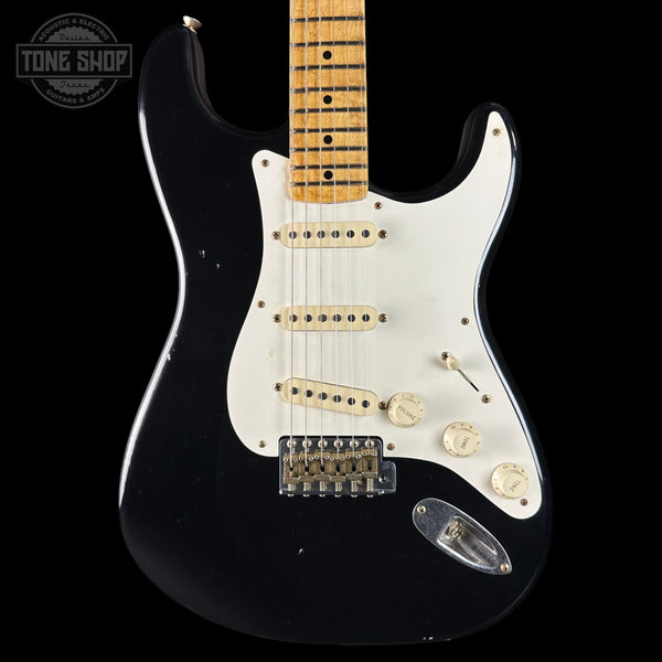 Black electric guitar with a white pickguard on a black background, featuring 'Tone Shop' branding.