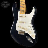 Black electric guitar with a white pickguard on a black background, featuring the Tone Shop logo.