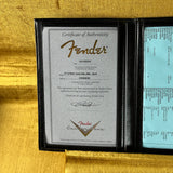 Fender certificate of authenticity in a black frame on a gold background