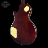 The back view of an electric guitar with a glossy dark reddish-brown finish, featuring cream-colored pickguard plates, shown against a solid black background.