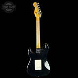 Black electric guitar with a visible brand logo on a black background