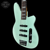Light blue bass guitar on a black background with 'Tone Shop' logo.