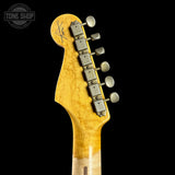 Close-up of a guitar headstock with tuning pegs on a black background, featuring the Tone Shop logo.