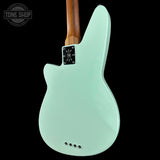 Electric guitar with a light green body and wooden neck on a black background, featuring the Tone Shop logo.