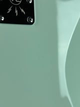 Close-up of a guitar with a brand logo on a light green background