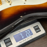 Digital scale displaying weight of a guitar neck on a wooden surface