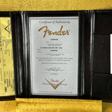 Fender certificate of authenticity in a black leather holder on a wooden surface