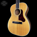 Acoustic guitar with a tortoiseshell pickguard on a black background, featuring the Tone Shop logo.