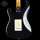 Black electric guitar with a wavy design on the back, brand logo visible.