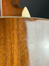 Close-up of a wooden guitar with a visible scratch on the surface.
