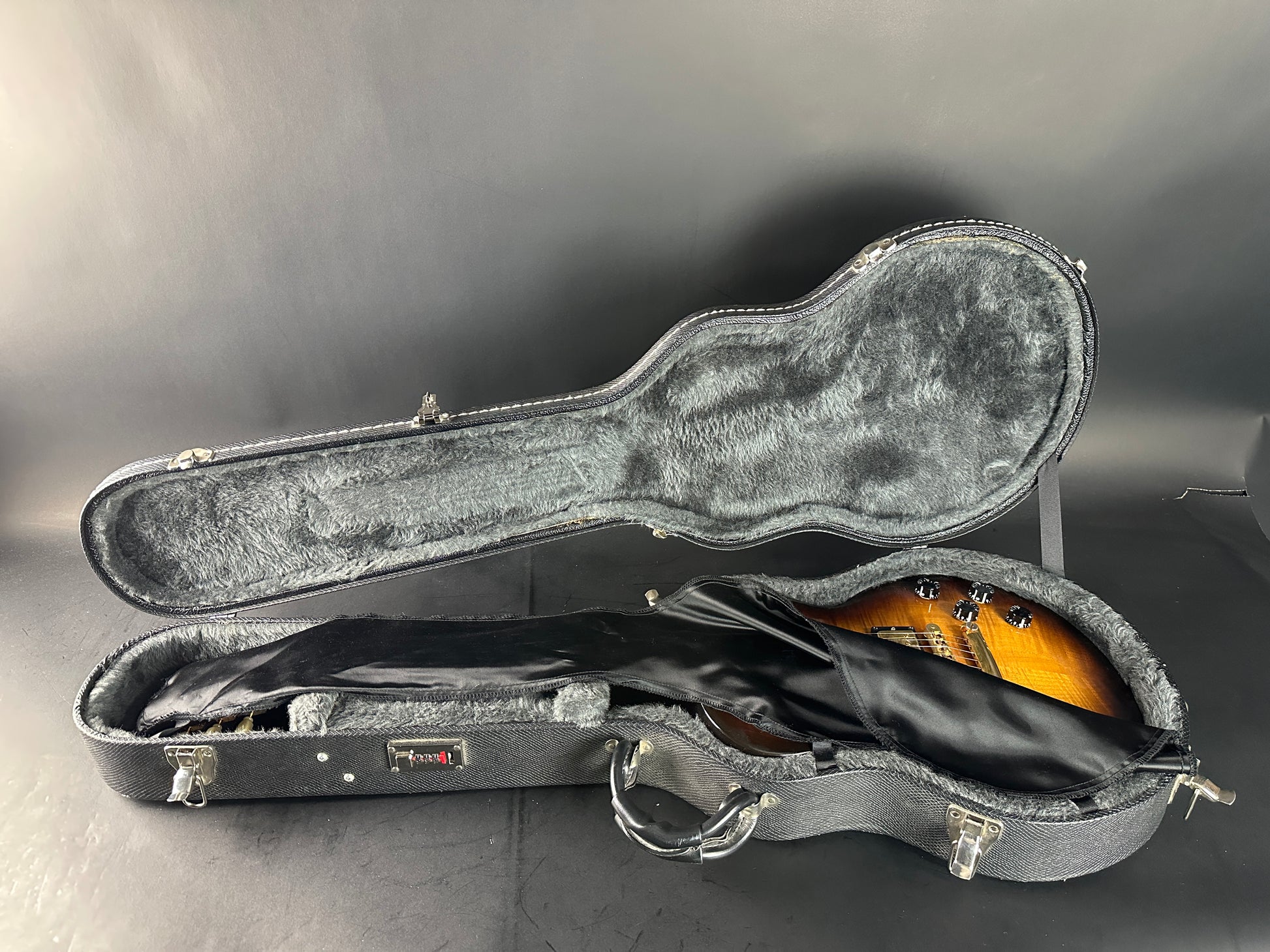 Guitar in an open black case on a gray background