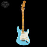 Blue electric guitar with a white pickguard on a black background, featuring the Tone Shop logo.