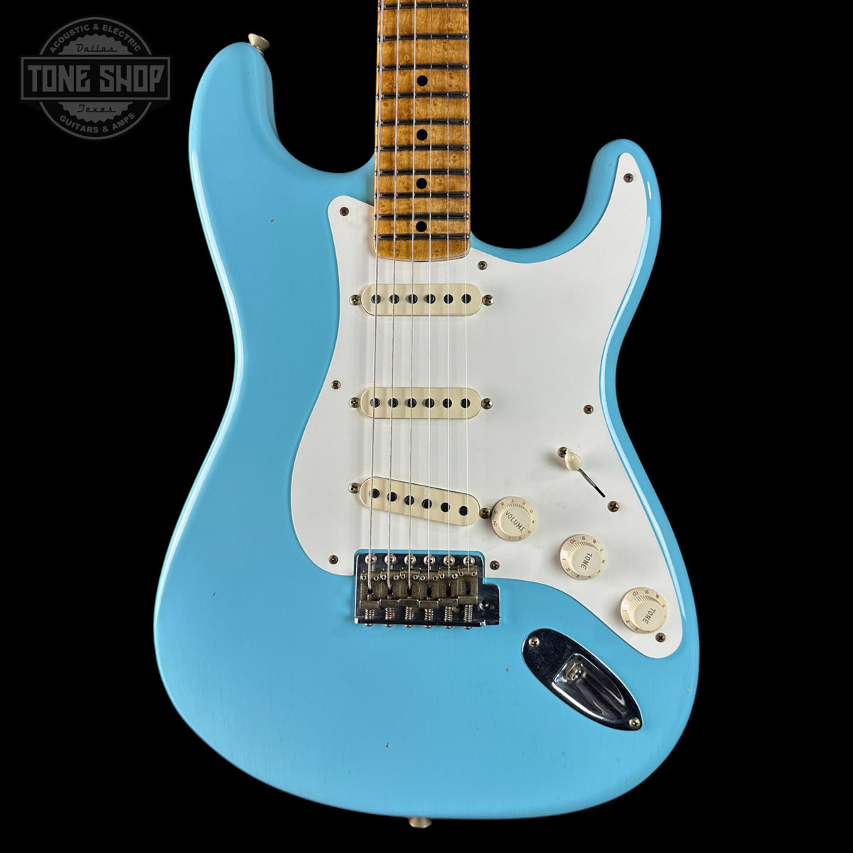 Blue electric guitar with a white pickguard on a black background, featuring the Tone Shop logo.