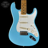 Blue electric guitar with a white pickguard on a black background, featuring the Tone Shop logo.