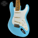 Blue electric guitar with a white pickguard on a black background, featuring the Tone Shop logo.