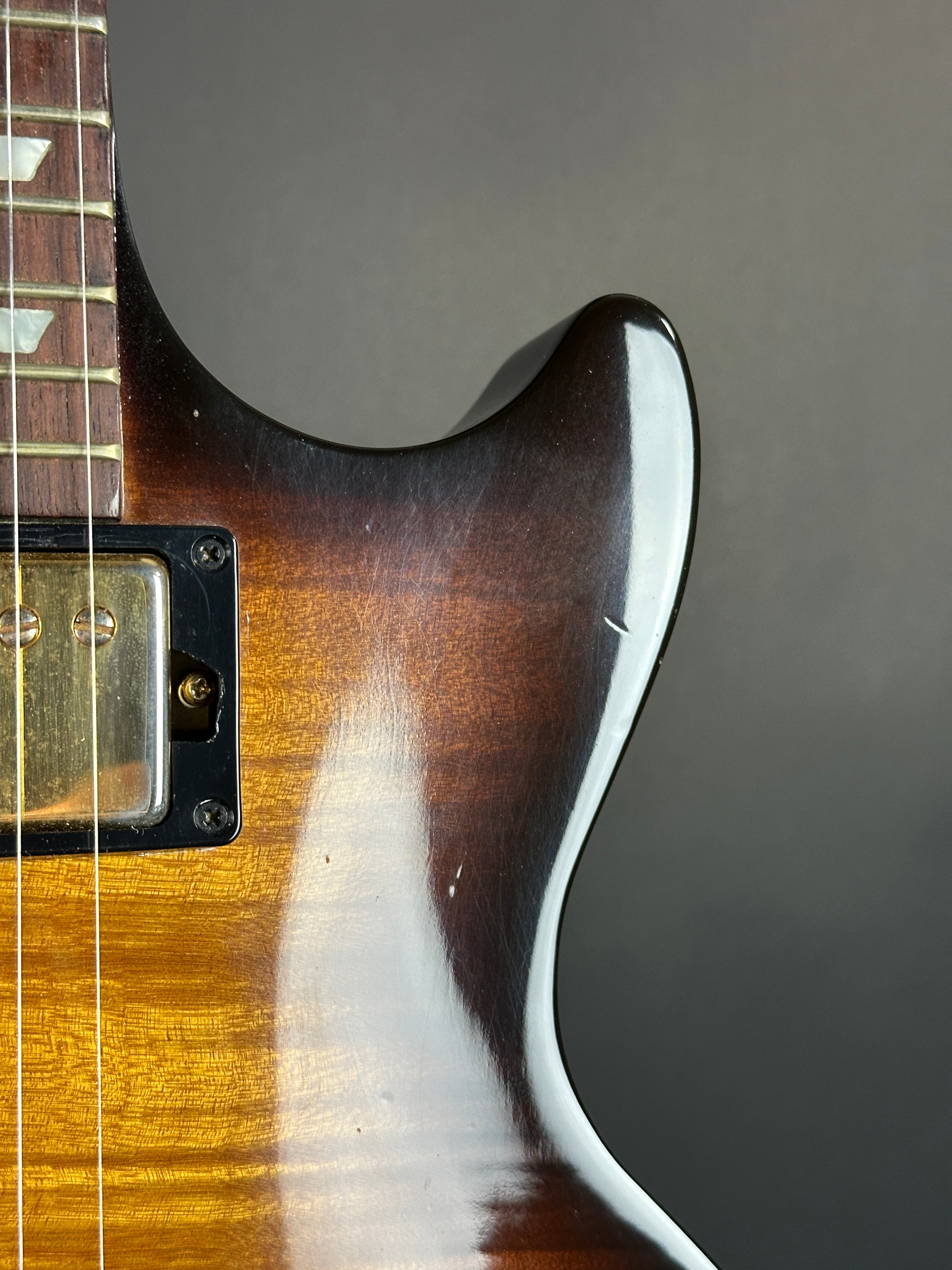 Close-up of a guitar's neck and headstock against a dark background
