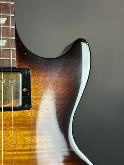 Close-up of a guitar's neck and headstock against a dark background