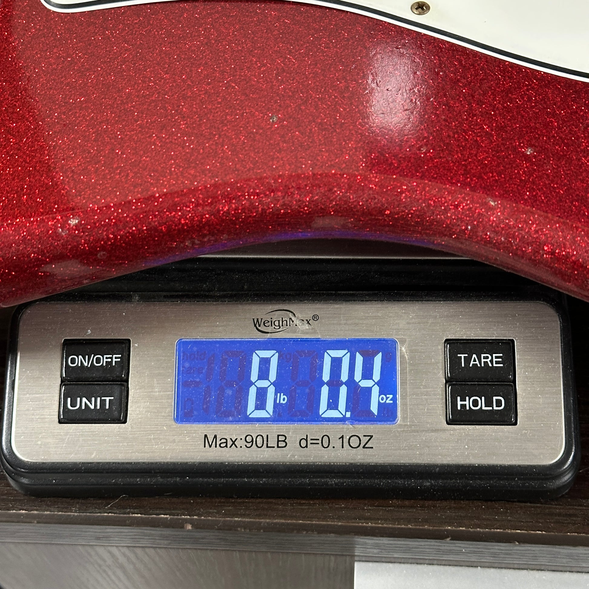Digital scale displaying weight with a red glittery object on top