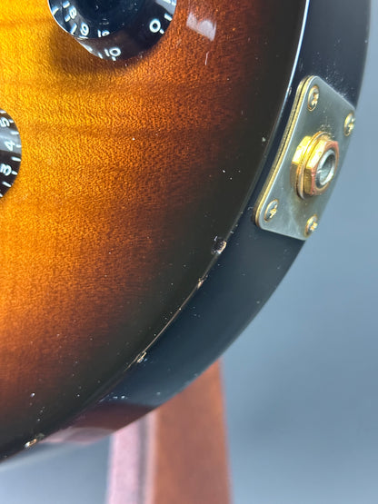 Close-up of a guitar headstock with a sunburst finish and gold tuning pegs.