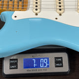 Blue electric guitar being weighed on a digital scale