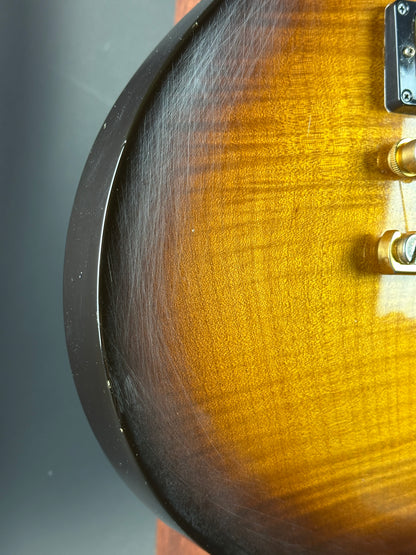 Close-up of a guitar's sunburst finish with pickguard and tuning pegs.