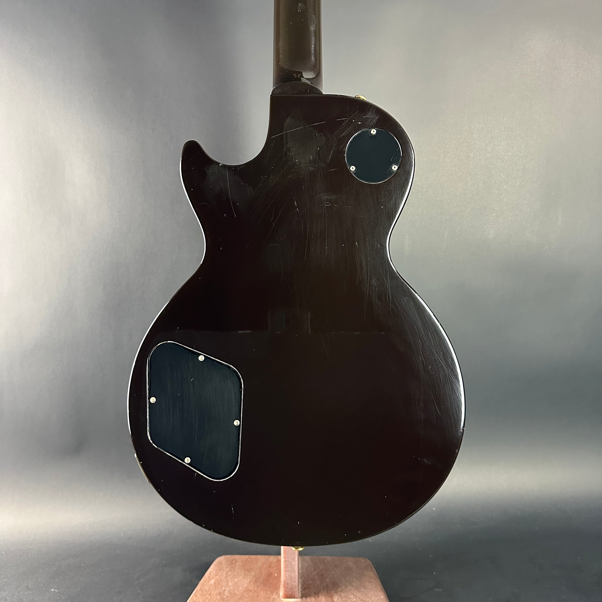 Black electric guitar on a stand against a gray background