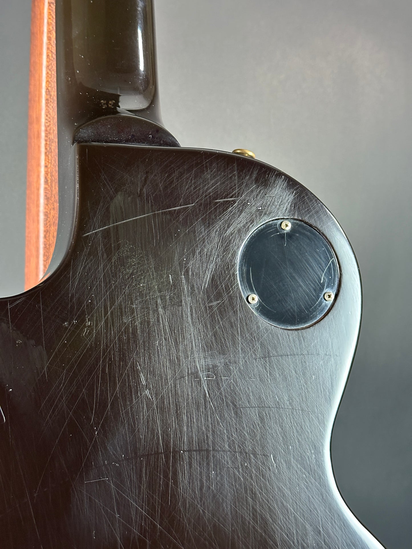 Close-up of a guitar neck with visible wear and tear on a gray background