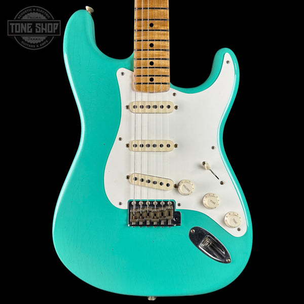 Turquoise electric guitar with a white pickguard on a black background, featuring 'Tone Shop' branding.