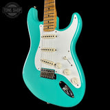 Turquoise electric guitar with a white pickguard on a black background, featuring the Tone Shop logo.