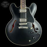 Black electric guitar with a visible brand logo on a black background