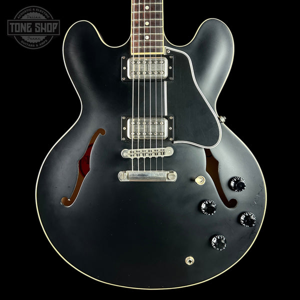Black electric guitar with a visible brand logo on a black background