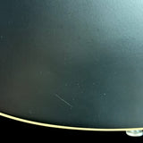 Close-up of a black guitar with visible scratch on the surface