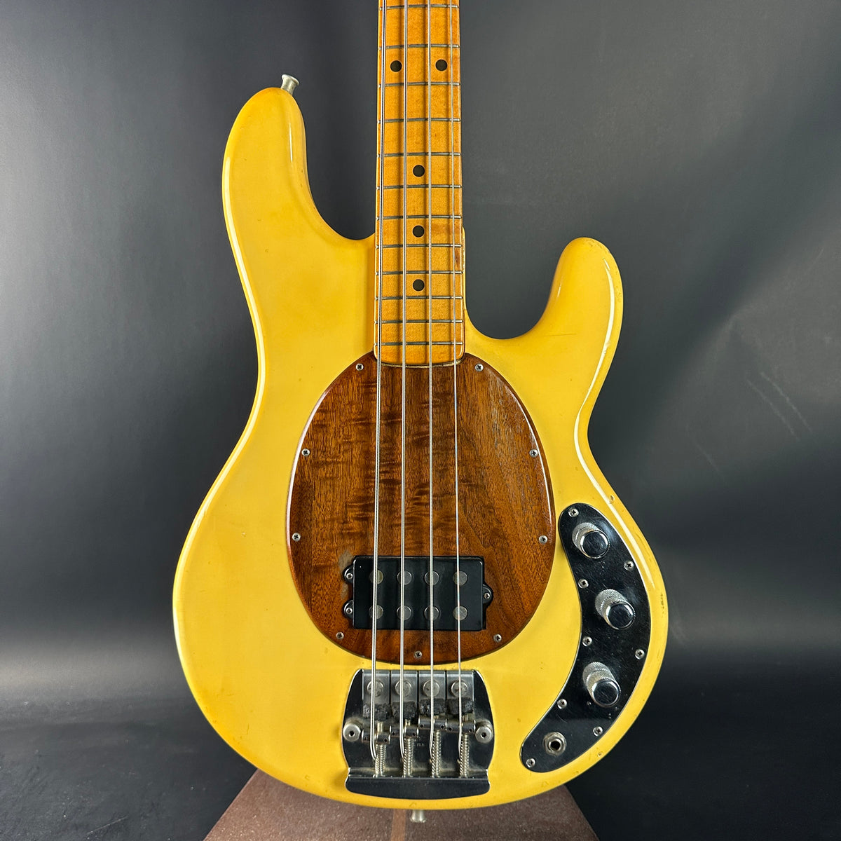 Yellow electric bass guitar on a dark gray background
